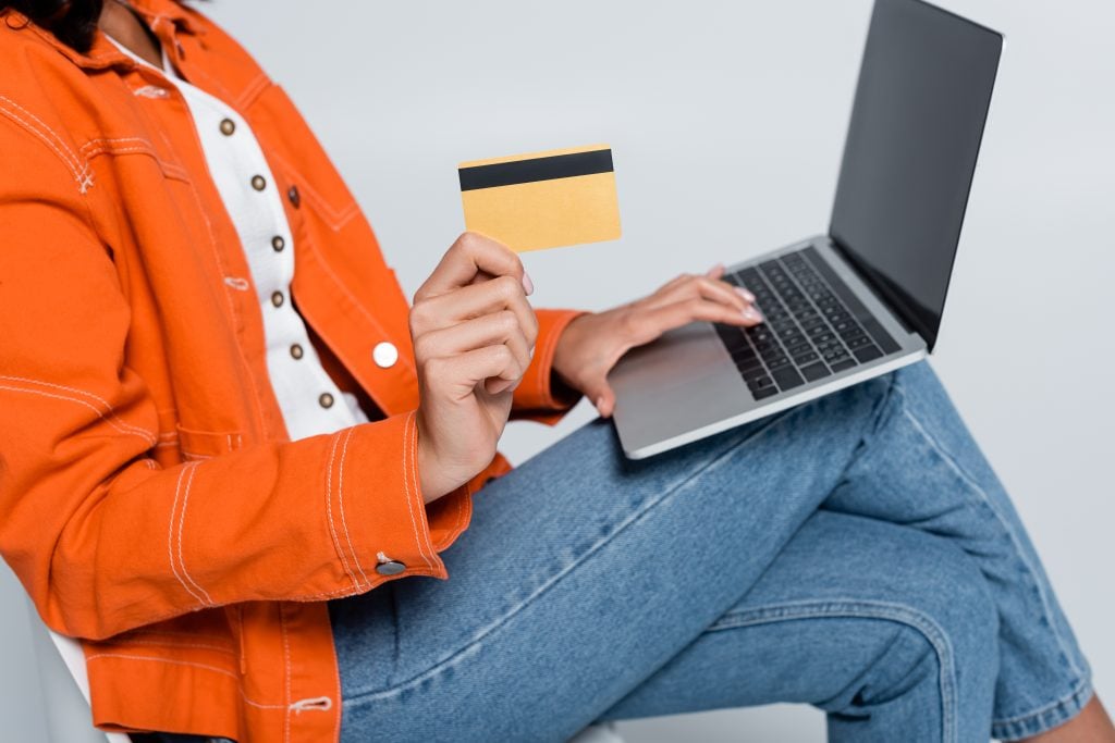 Woman holding a credit card while using a laptop.